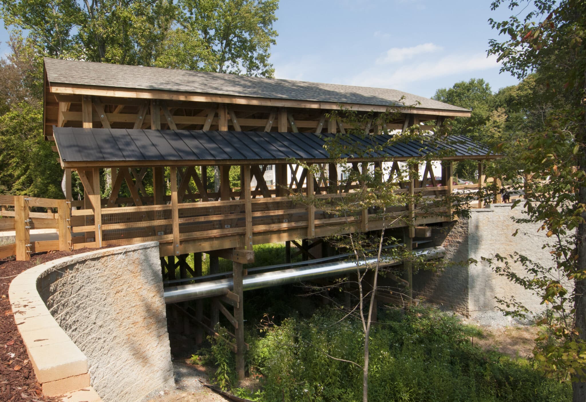 Side profile of covered vehicular timber bridge and concrete abutments for Deacon's Station in Winston Salem, NC designed and built by York Bridge Concepts.