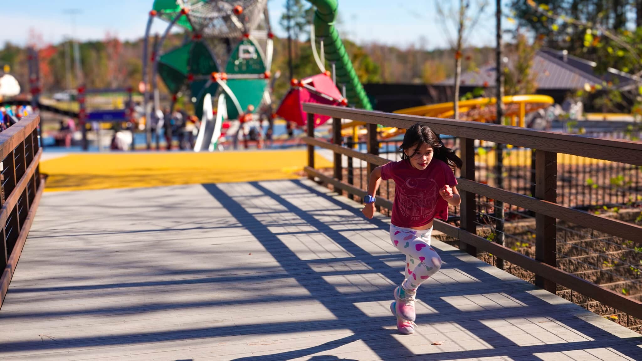 Girl running across the timber pedestrian bridge built by YBC in Apex, NC